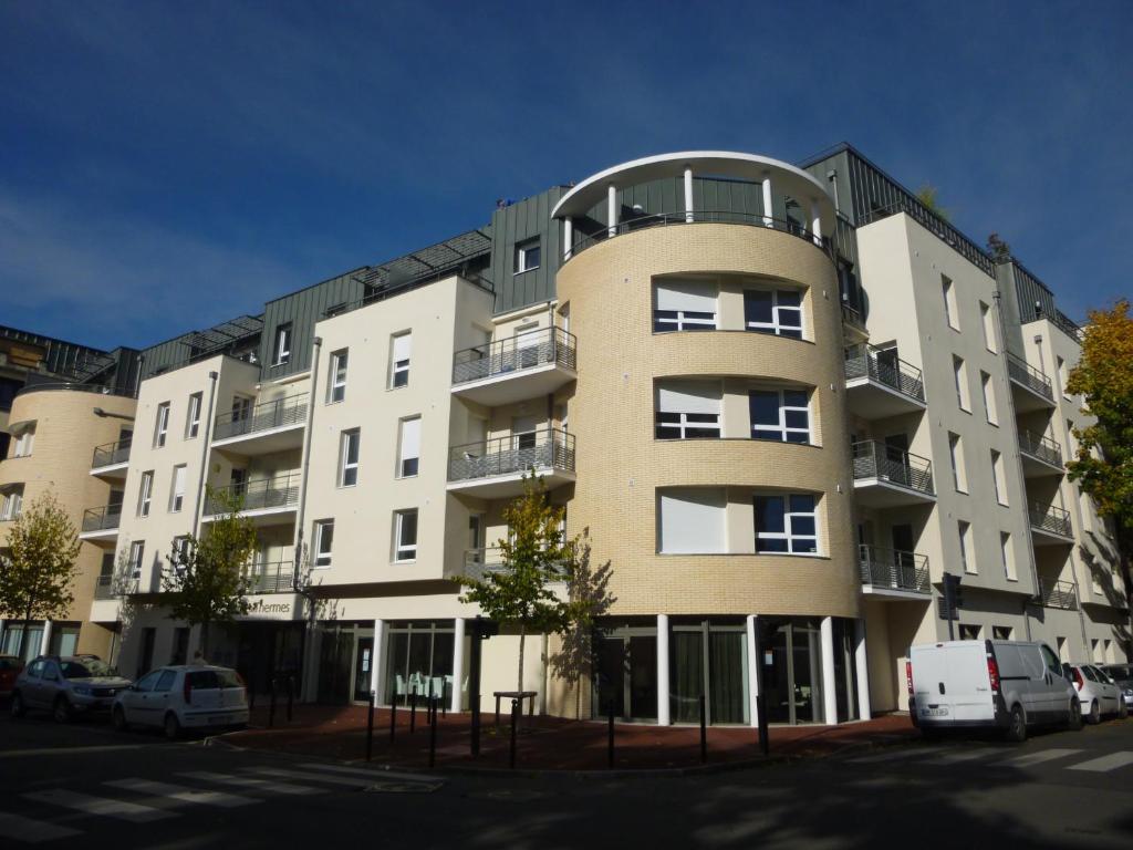 an apartment building with cars parked in front of it at La Résidence Therm’Appart in Vichy