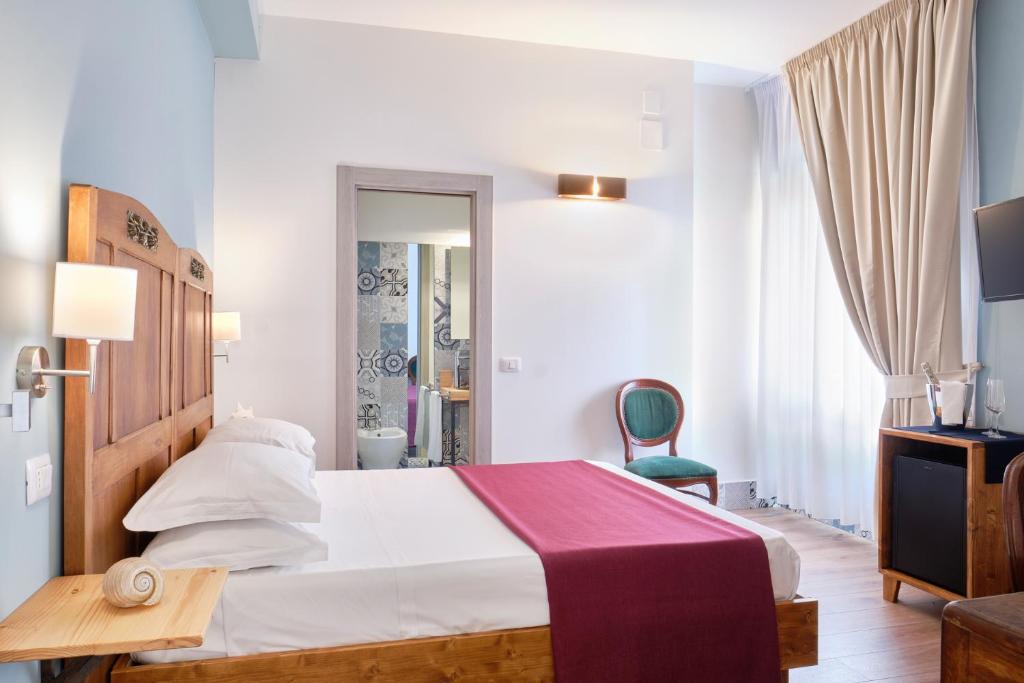 a hotel room with a bed and a chair at La Via del Porto Charme Rooms in Agropoli