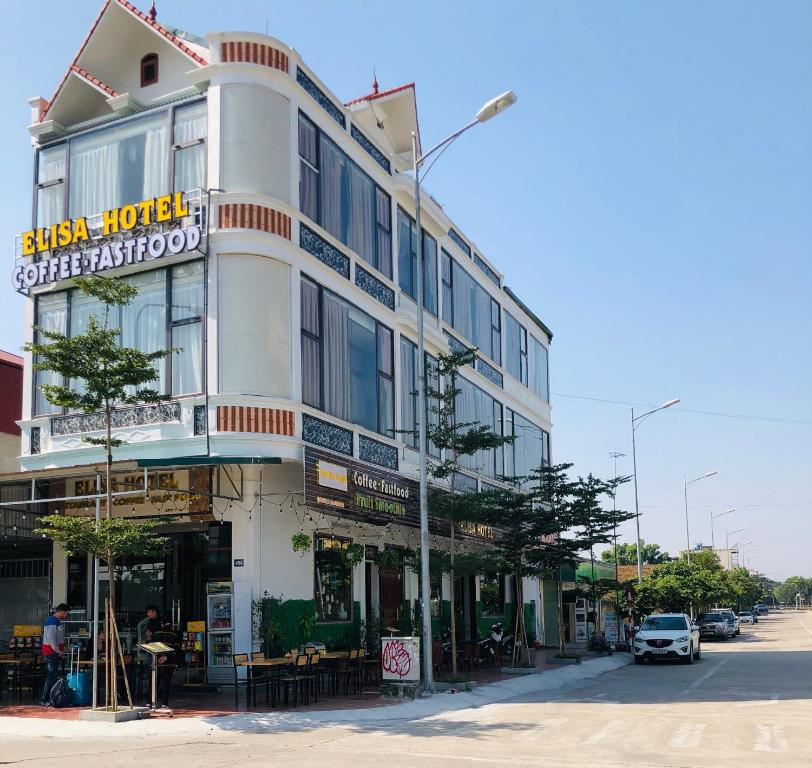 un grande edificio bianco su una strada cittadina con un'auto di Elisa Hotel a Ninh Binh