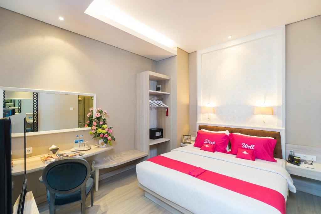 1 dormitorio con cama con almohadas rojas y escritorio en Royal City Hotel, en Yakarta