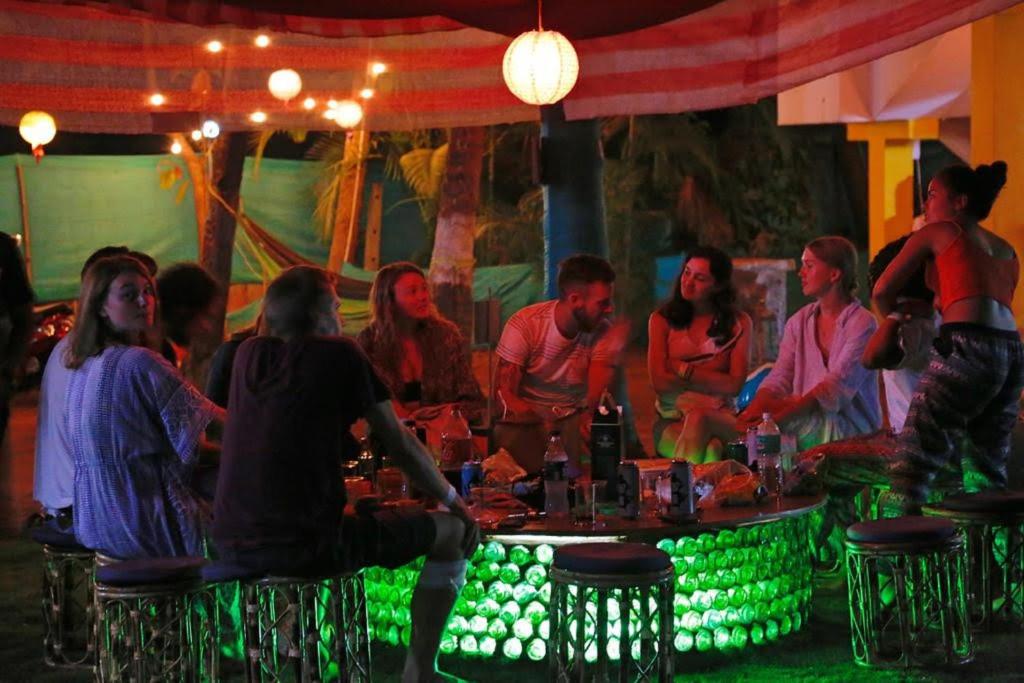 a group of people sitting around a table with green lights at The Lost Hostel, Goa - Palolem Beach in Palolem