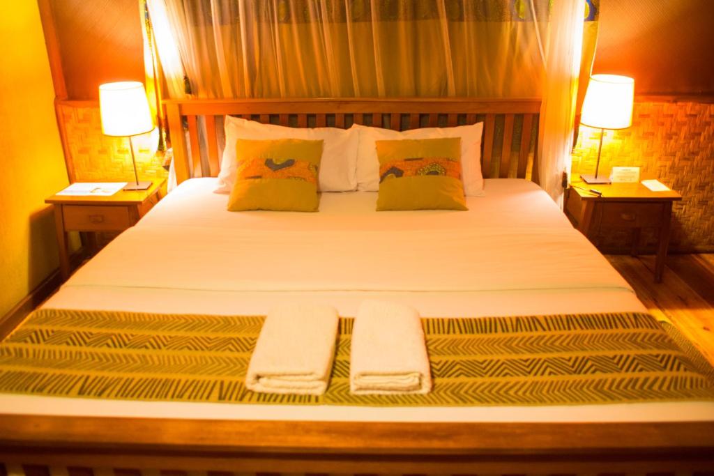 a bedroom with a bed with two towels on it at Queen Elizabeth Bush Lodge by NATURE LODGES LTD in Bushenyi