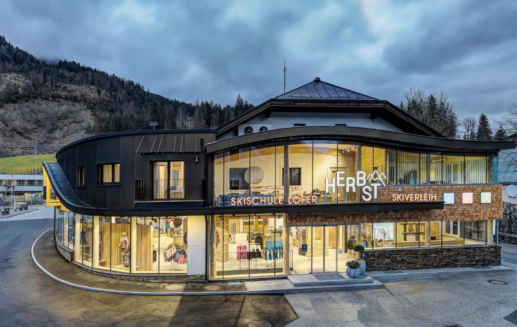 a large building with glass windows in a parking lot at Herbst Wohnerlebnis in Lofer