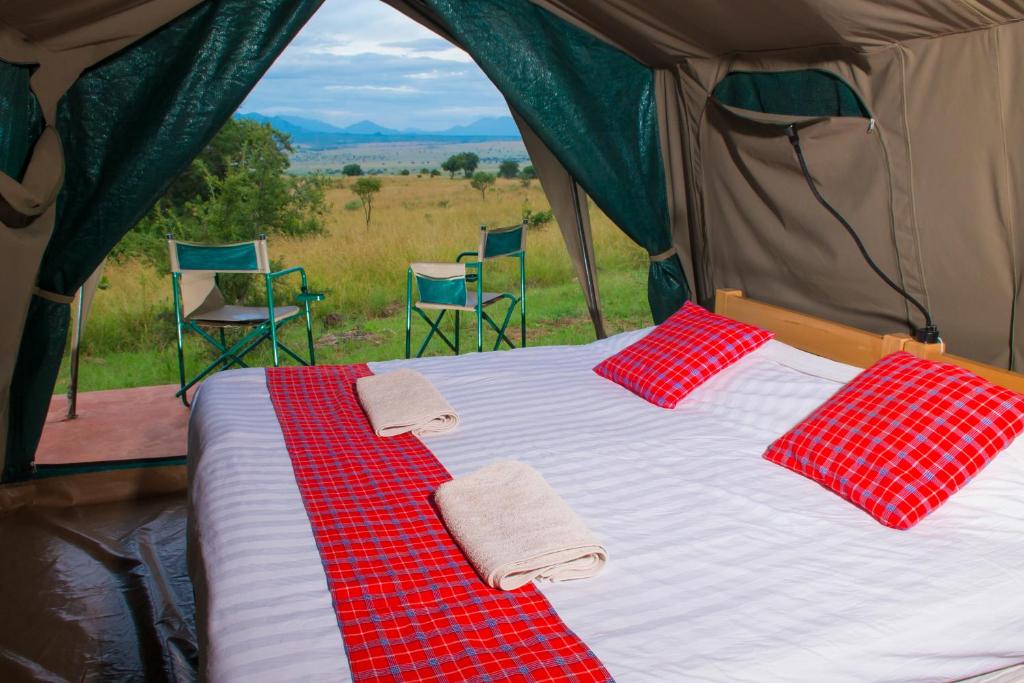 ein Bett in einem Zelt mit zwei Stühlen in der Unterkunft Kidepo Savannah Lodge by NATURE LODGES LTD in Loitanit