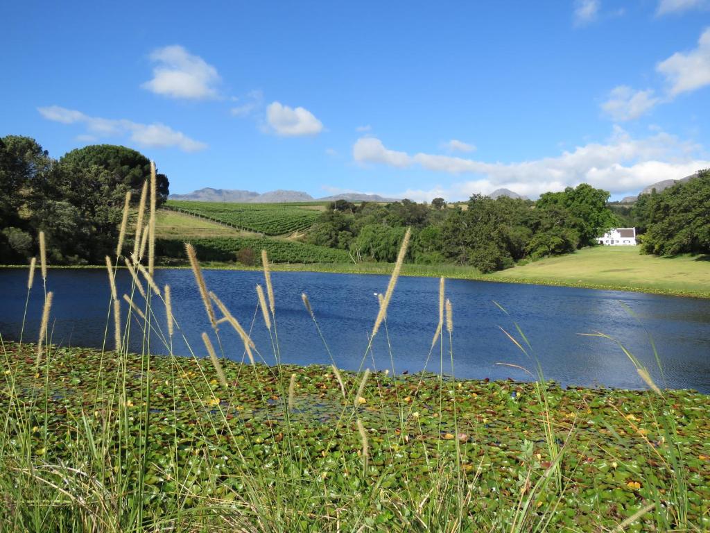 a view of a lake with a house in the background at Navarre Farm Cottages in Stellenbosch