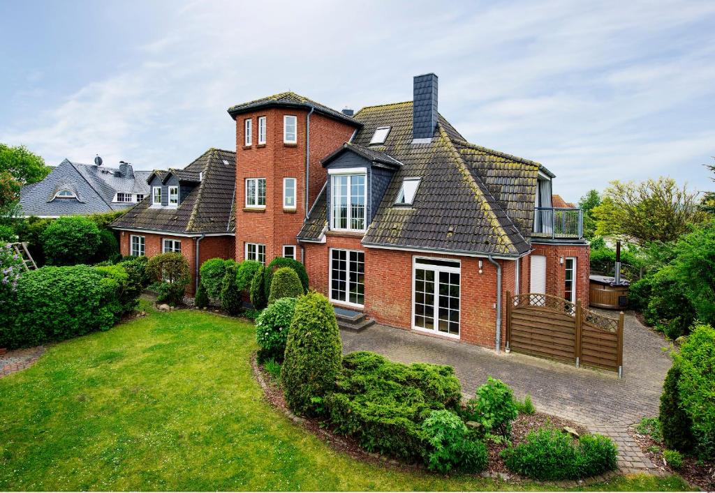 a large red brick house with a yard at Ferienwohnung im Poolhaus mit Ostseeblick in Wittenbeck