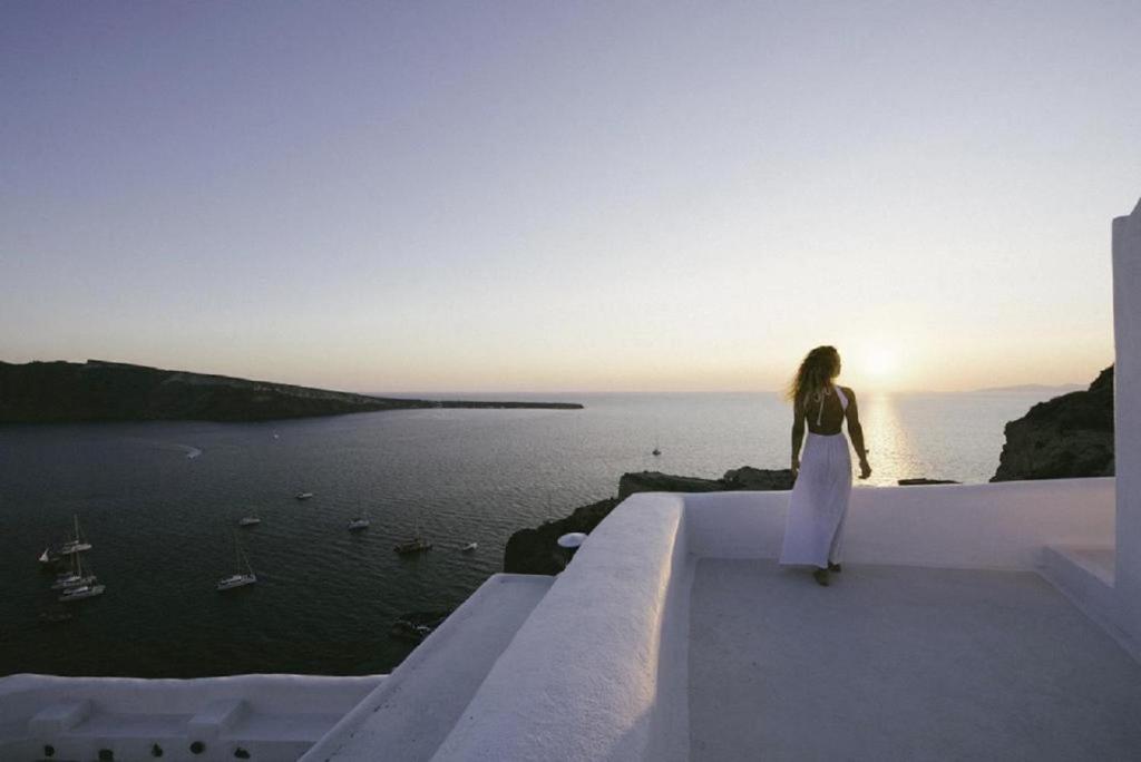 a woman standing on the edge of a building looking at the ocean at The Architect's Cave House in Oia