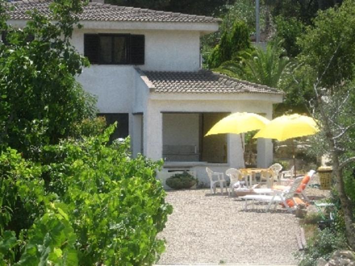 a patio with two yellow umbrellas in front of a house at Villa Asinara in Platamona
