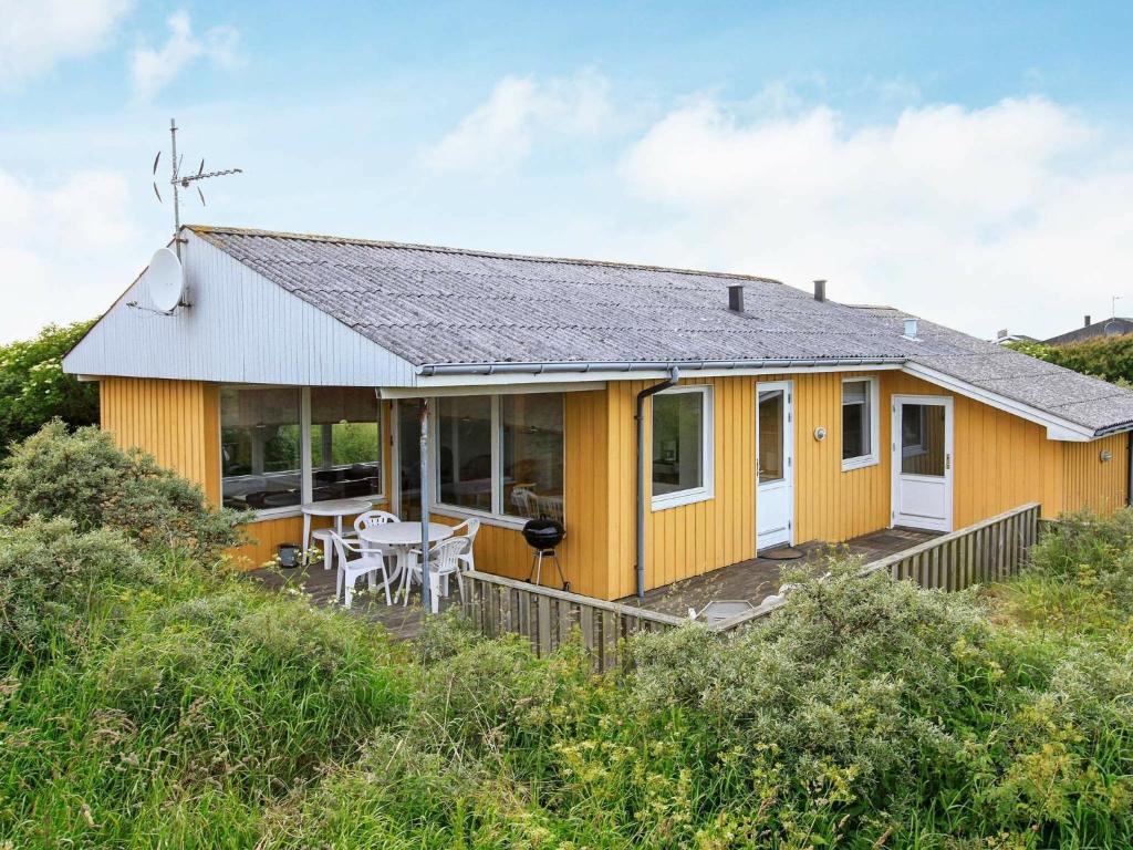 a yellow house on a hill with a table at 8 person holiday home in Hj rring in Hjørring