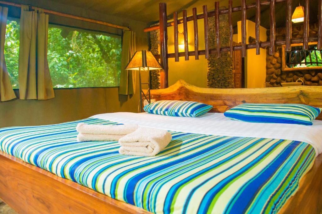 1 dormitorio con 1 cama con toallas en Kibale Forest Camp by NATURE LODGES LTD en Kyenjojo