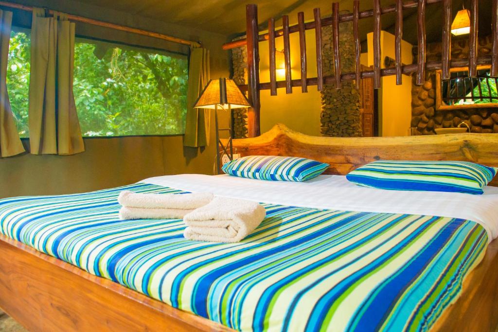 a bedroom with a bed with towels on it at Kibale Forest Camp by NATURE LODGES LTD in Kyenjojo