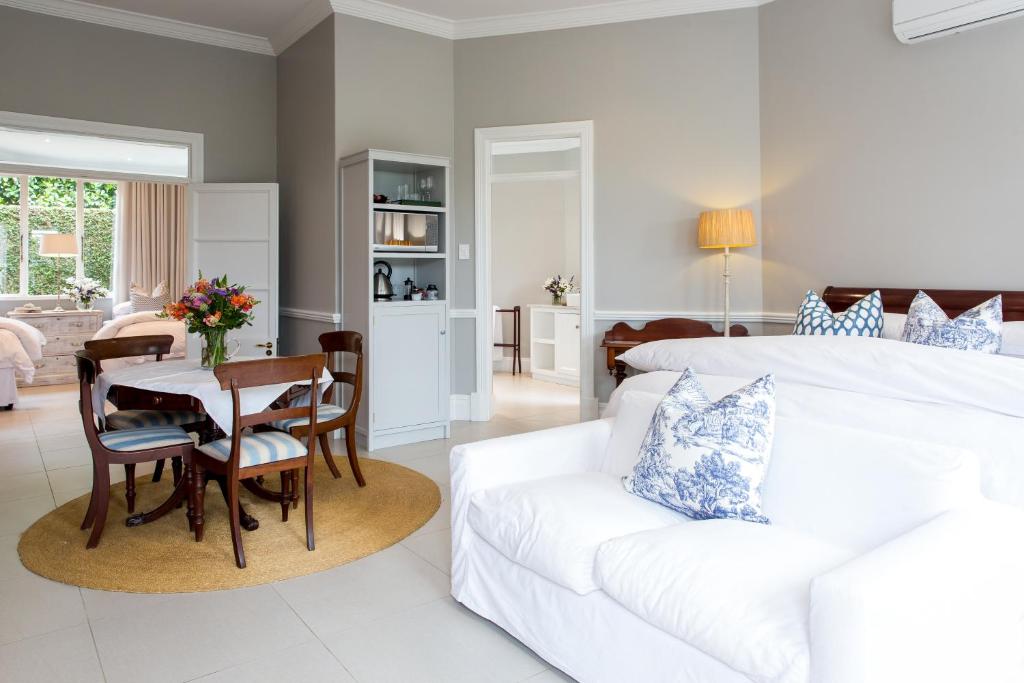 a bedroom with a white bed and a white couch at Lexden Guesthouse in Pietermaritzburg