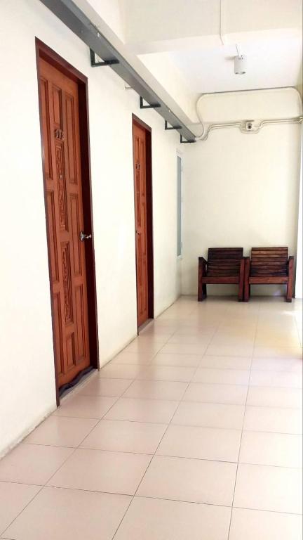 an empty room with two doors and a bench at Ban Mae Boonthong in Lampang