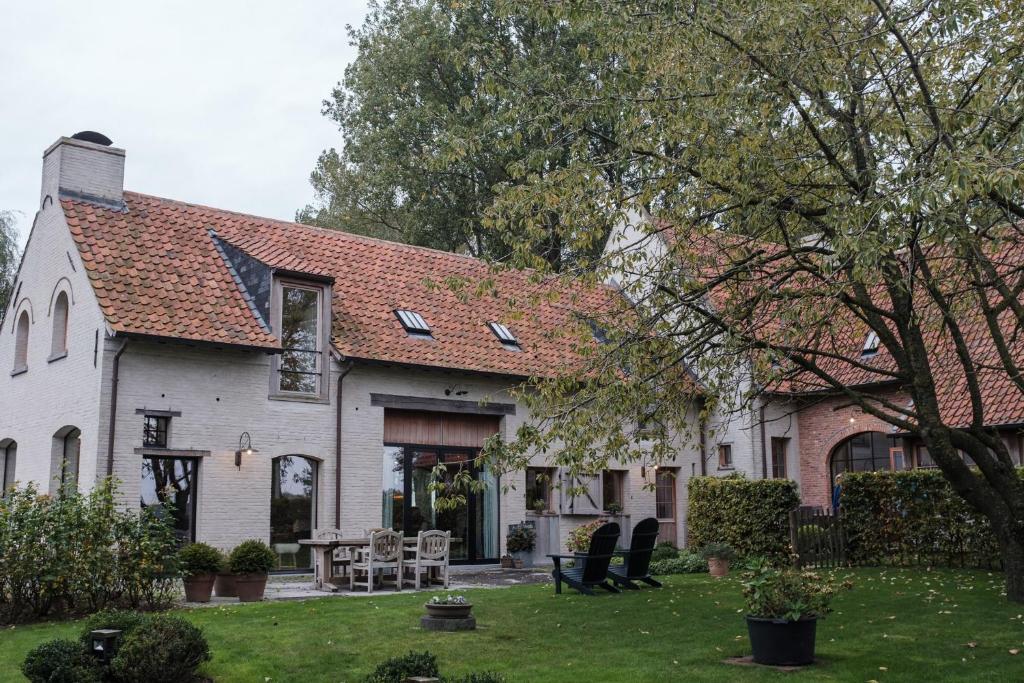 Casa blanca con techo rojo y patio en De Zonnebrug Dijkhoeve, en Saint-Laureins