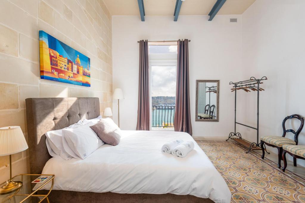 ein Schlafzimmer mit einem großen weißen Bett und einem Fenster in der Unterkunft Harbour Heights in Valletta