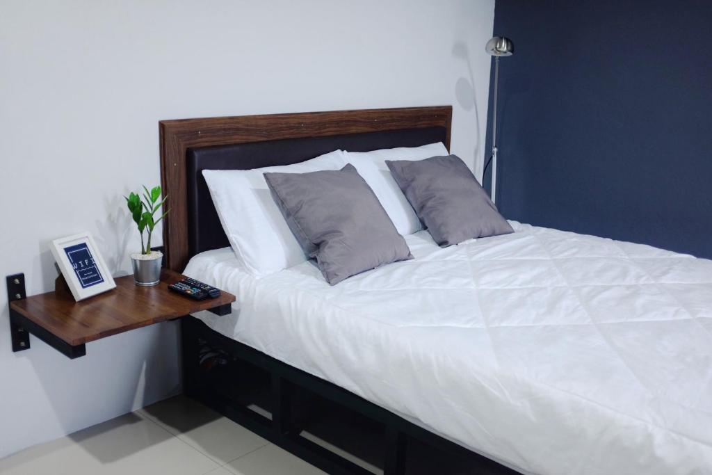 a bedroom with a white bed with a wooden table at The room Apartment in Surat Thani