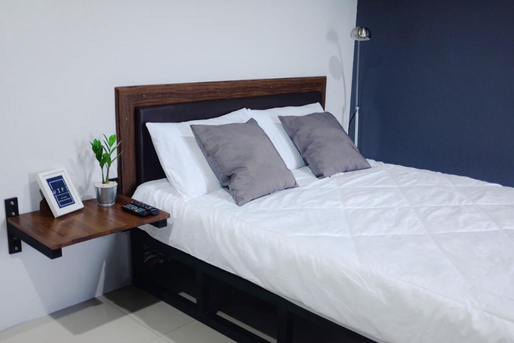 a bedroom with a white bed with a wooden table at The room Apartment in Suratthani