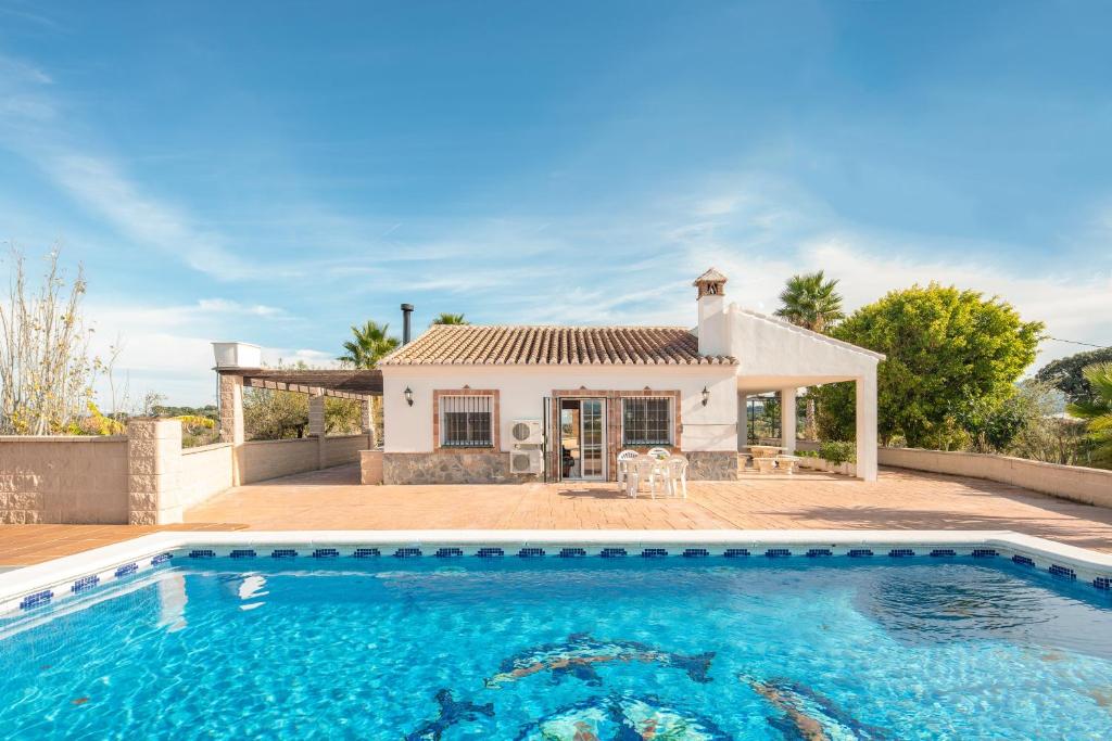 une villa avec une piscine en face d'une maison dans l'établissement Chalet andaluz Los Alberos, à Coín