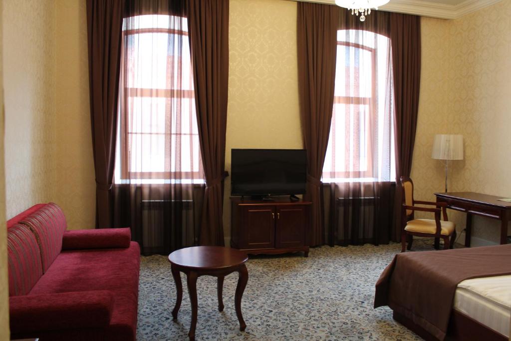 a hotel room with a couch and a tv and curtains at Astrakhanskaya Hotel in Astrakhan