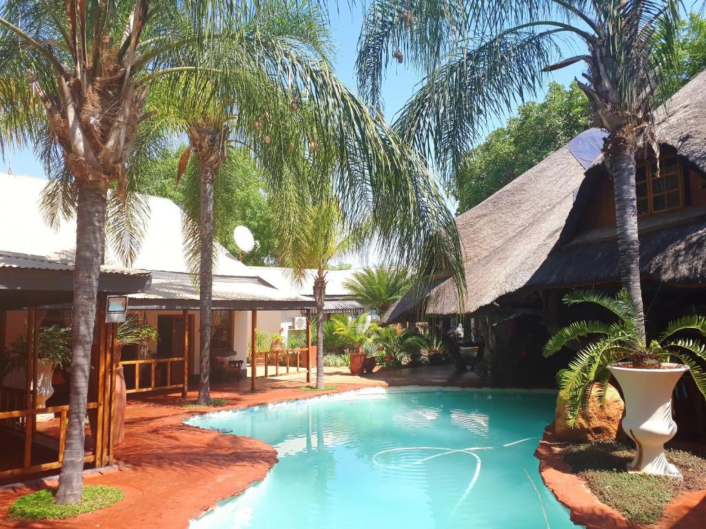 a resort with a swimming pool with palm trees at Dei Gratia Guest House in Musina