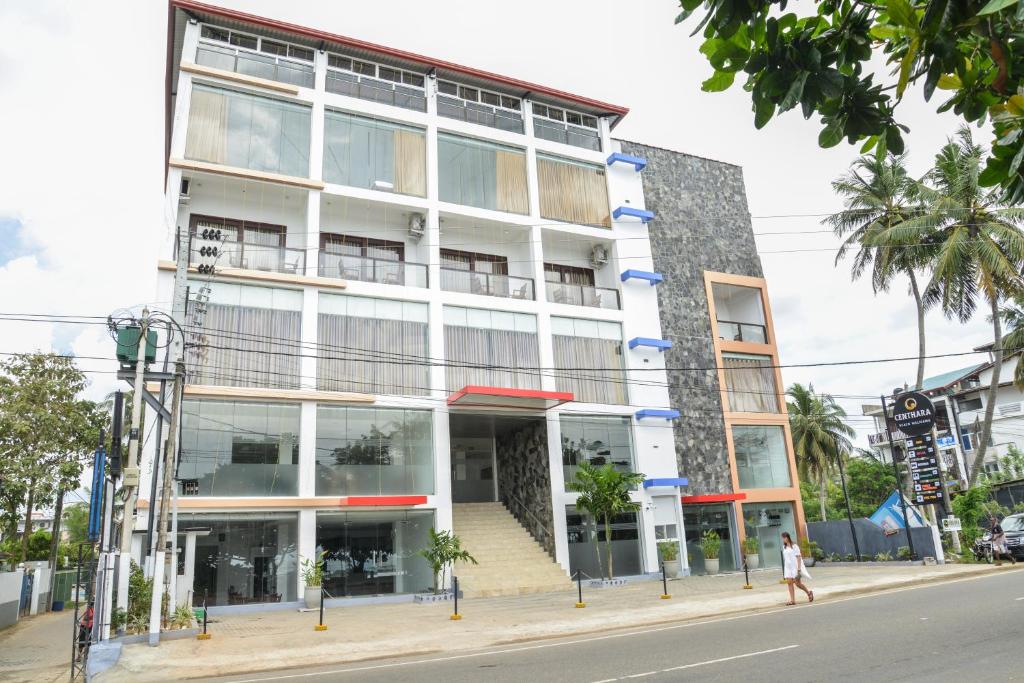 a building on a street with a person walking in front of it at Centhara Beach Weligama in Weligama