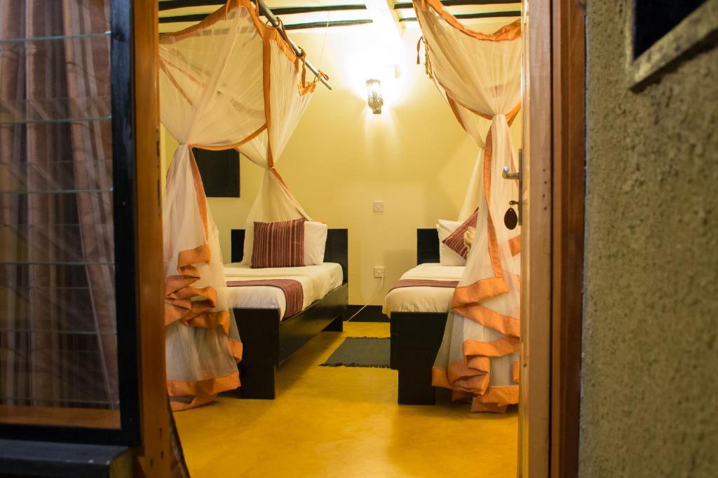 Pakwach EastにあるFort Murchison Lodge by NATURE LODGES LTDのベッド2台と出入り口が備わる小さな客室です。