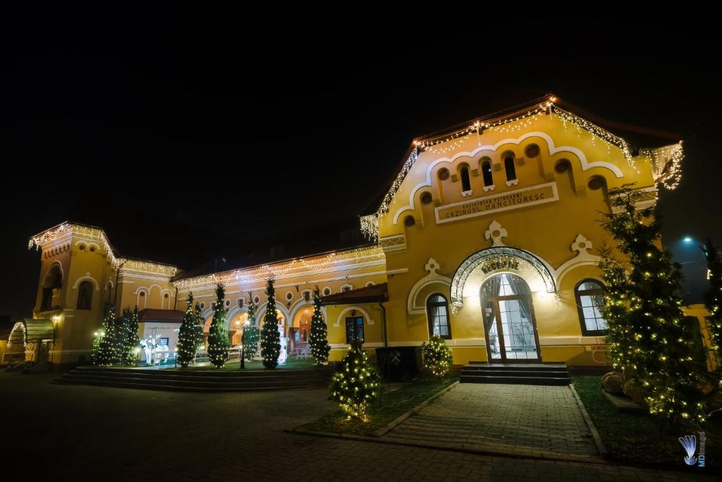 Um edifício amarelo com árvores de Natal à frente. em Hotel La Belle Epoque em Petroşani