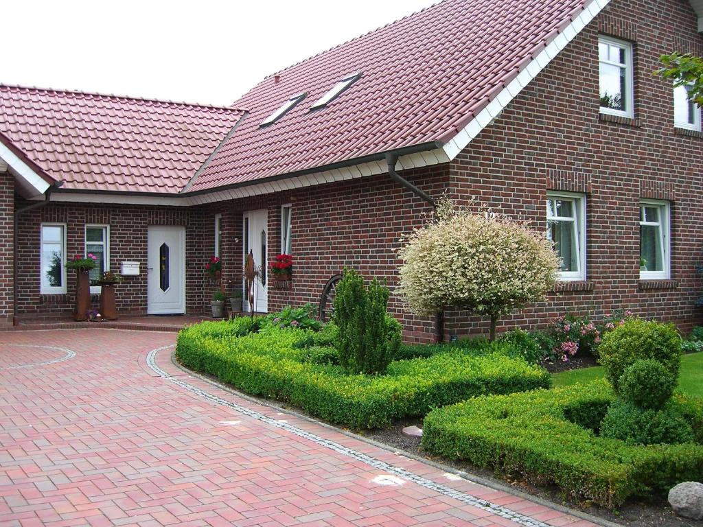 ein Backsteinhaus mit rotem Dach und einer Ziegelsteinfahrt in der Unterkunft Ferienwohnung Rossis Nüst, 31516 in Uplengen