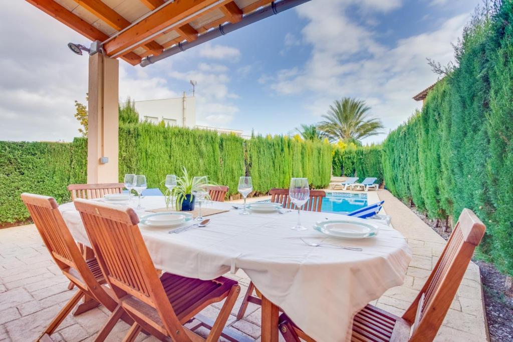 a table and chairs on a patio with a fence at YupiHome Villa Roser in Alcudia