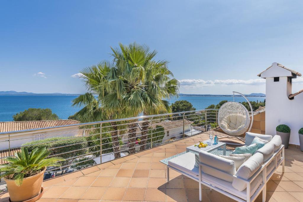 einen Balkon mit einem Sofa und Meerblick in der Unterkunft YupiHome Villa Alcanada - Family only in Port d'Alcúdia