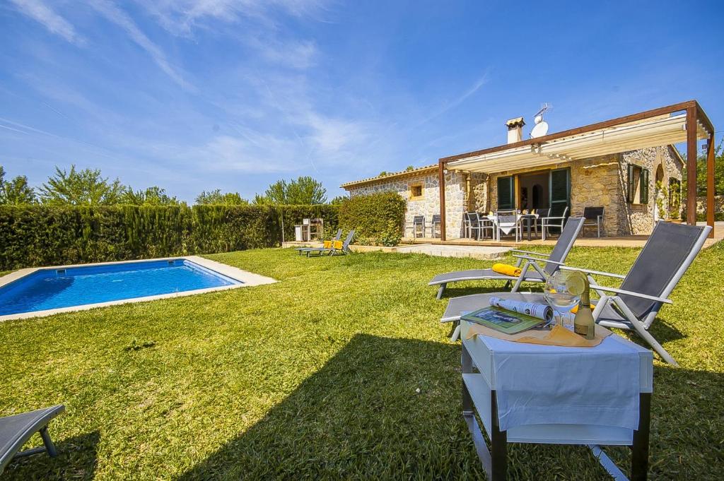 a backyard with a pool and chairs and a house at YupiHome Finca Dels Horts in Lloseta