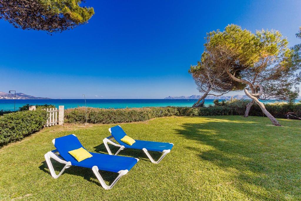 dos sillas azules sentadas en el césped cerca del océano en YupiHome Villa de les Aguiles, en Alcudia