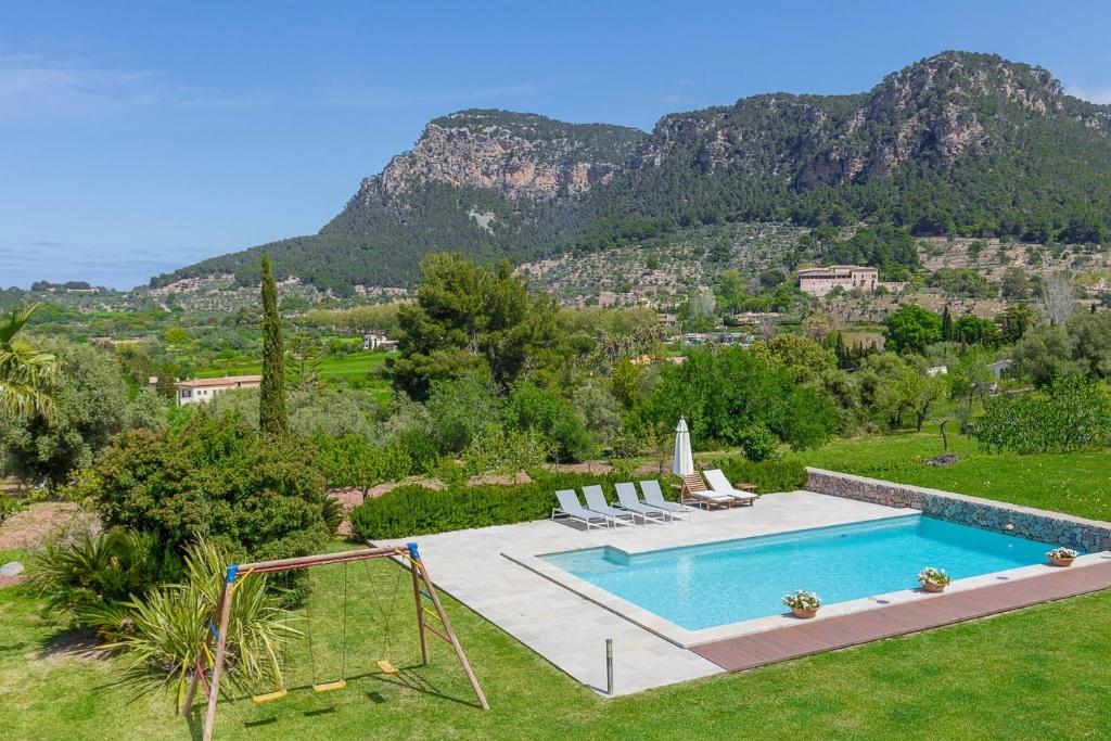 ein Schwimmbad in einem Garten mit Bergen im Hintergrund in der Unterkunft YupiHome Villa Son Beltran Valldemossa in Valldemossa