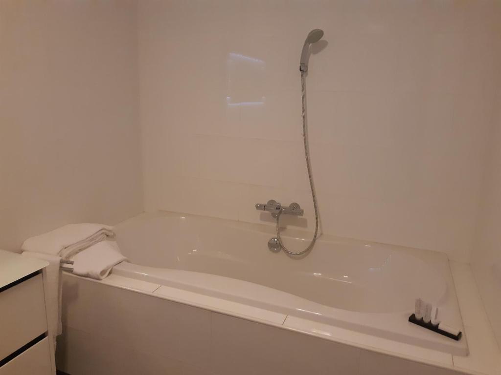 a bathroom with a bath tub with a shower at Hotel Johannes Vermeer Delft in Delft