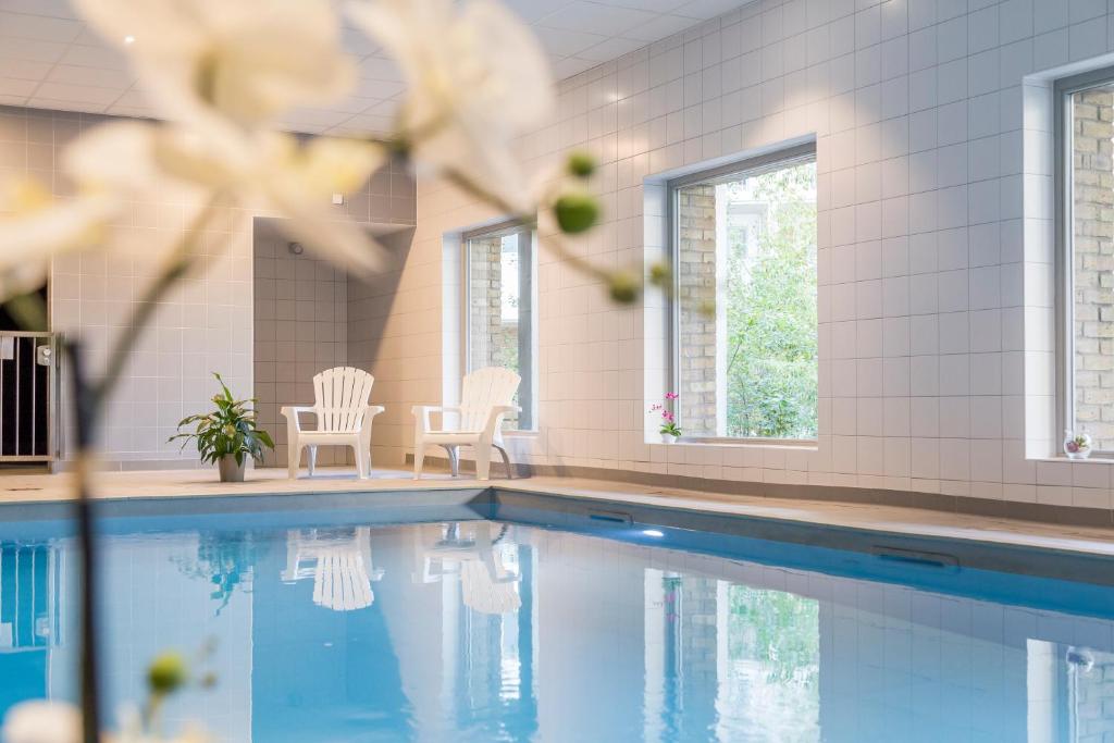 - une piscine avec 2 chaises et une table dans l'établissement Néméa Appart-Hôtel Elypséo, à Strasbourg