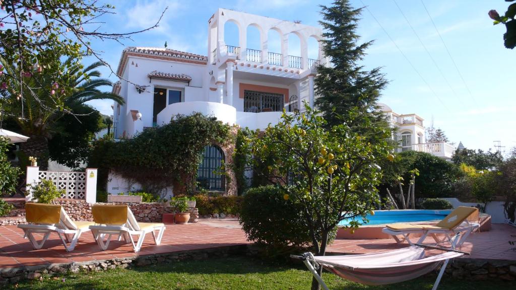 內爾哈的住宿－Casa los Arcos，白色的房子,配有椅子和游泳池