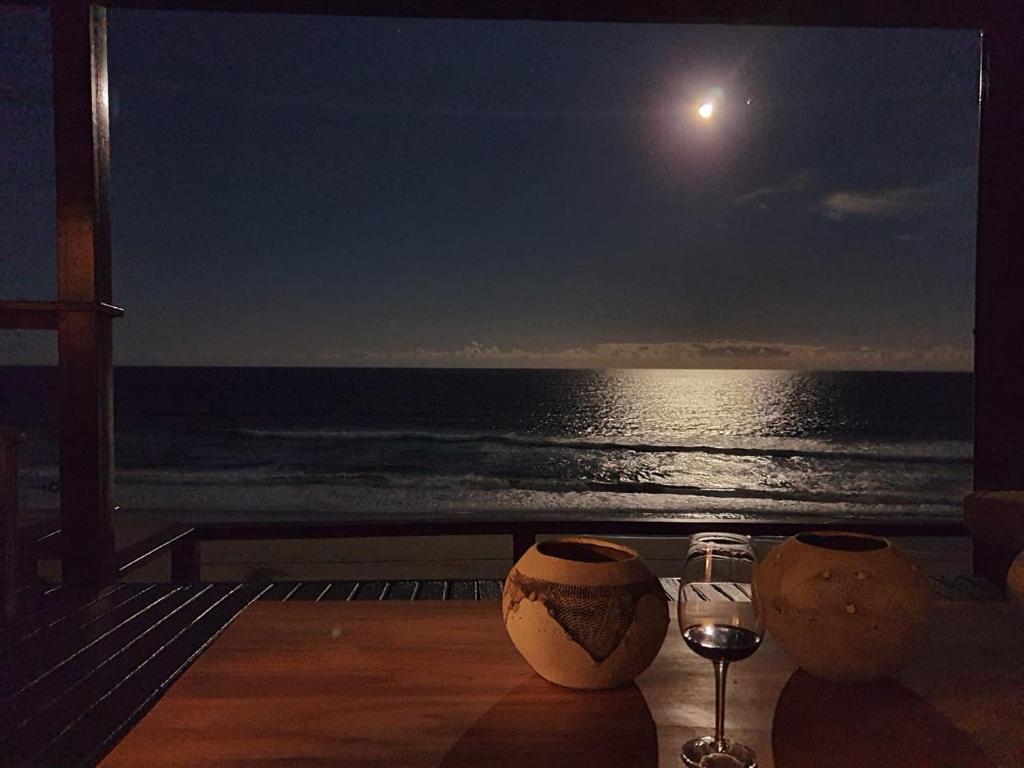 einen Tisch mit einem Glas Wein und Meerblick in der Unterkunft Mar Azul 4 in Ponta Malangane