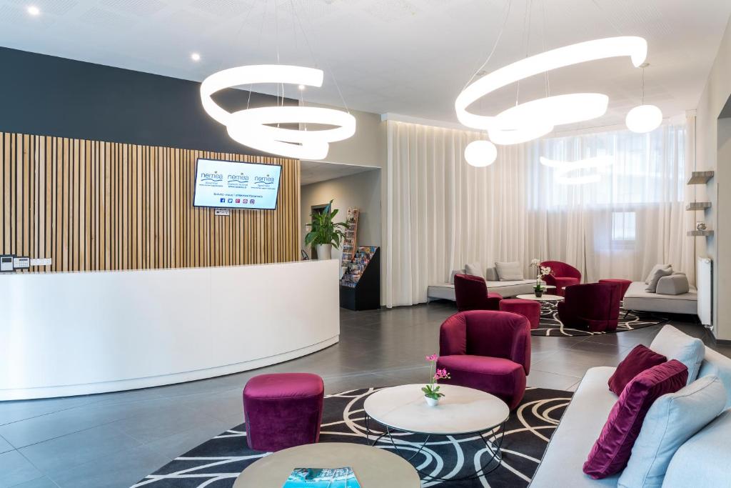 - un hall avec des chaises violettes et une réception dans l'établissement Nemea Appart Hotel Elypseo Strasbourg Port, à Strasbourg