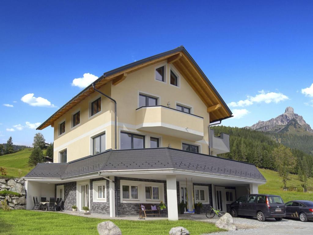 a house in the mountains with cars parked in front at Ferienwohnung Bergblick in Filzmoos