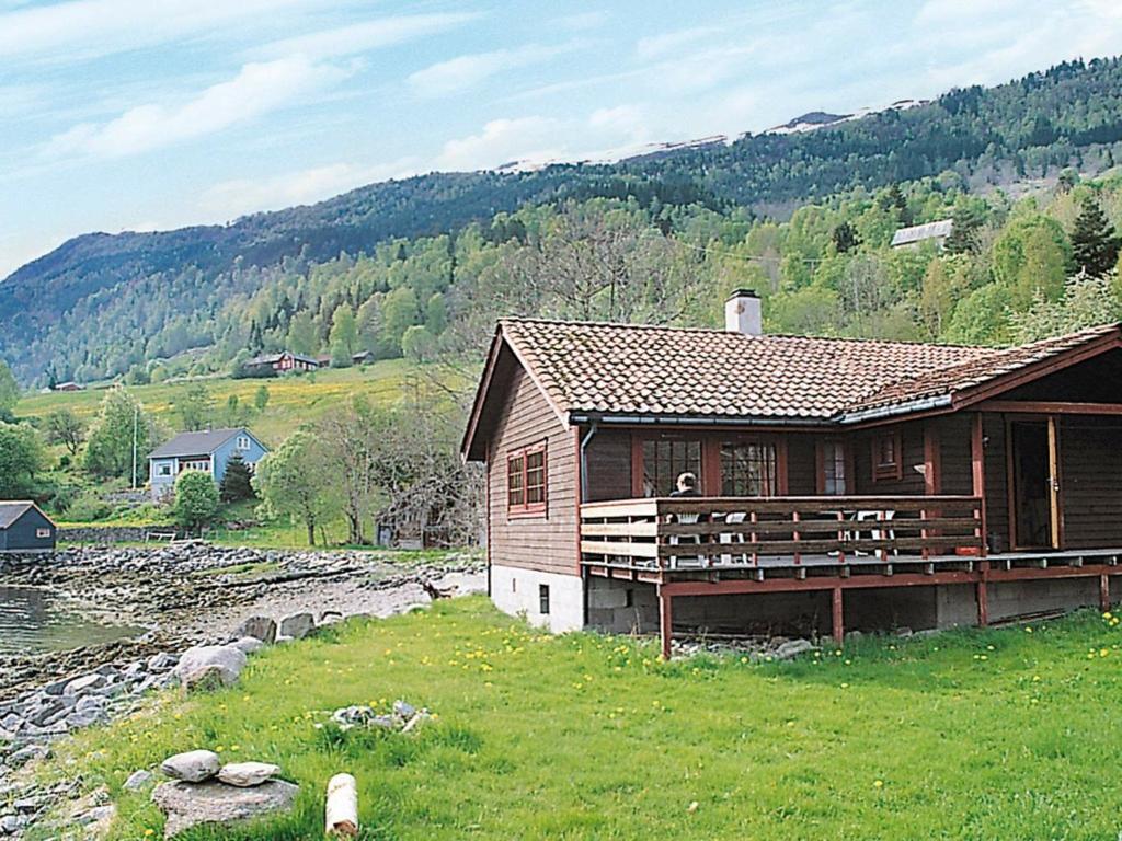 a wooden cabin in a field next to a river at Three-Bedroom Holiday home in Nordfjordeid 2 in Heggjafrislia