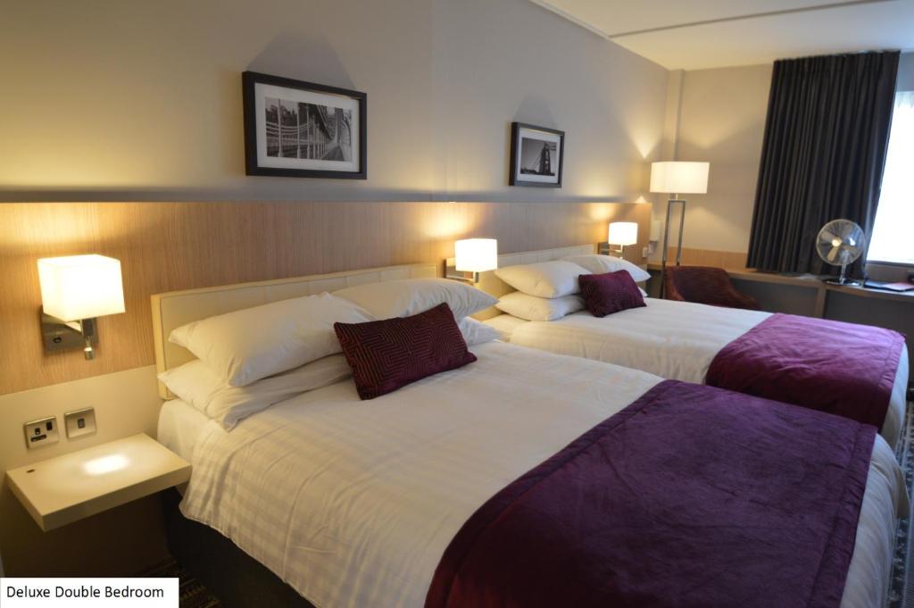 a hotel room with two beds and two lamps at Lancaster Hotel in Uxbridge