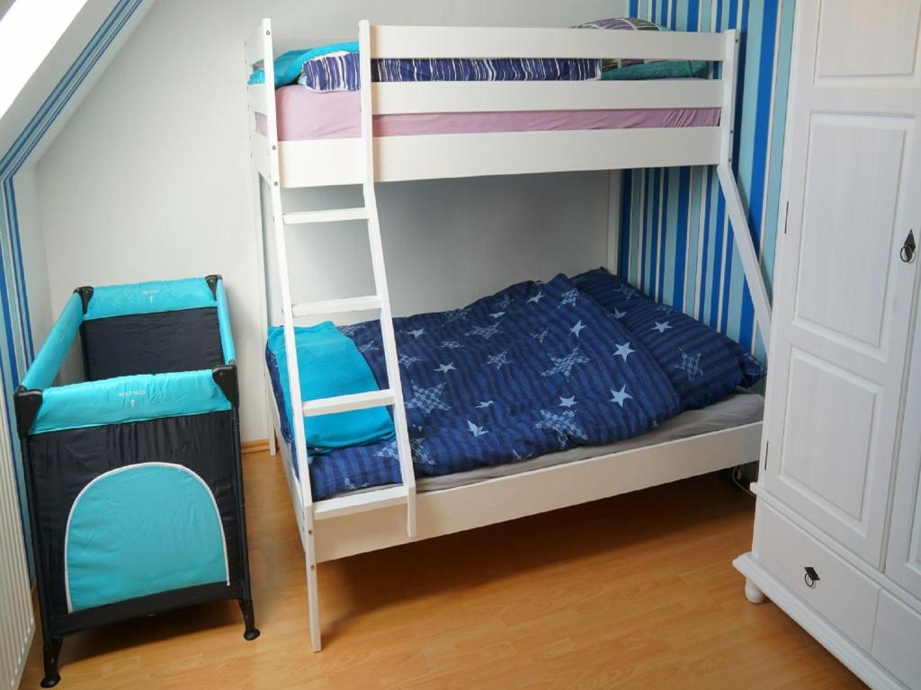 a bunk bed with a ladder and a chair in a room at Ferienwohnung an der Au in Taarstedt