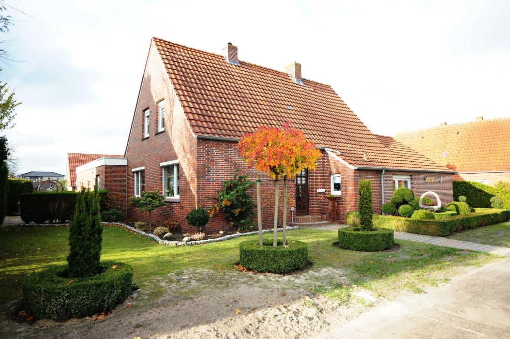 a red brick house with a tree in the yard at Ferienwohnung Frieda, 65207 in Moormerland