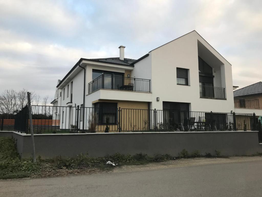 a white house with a fence in front of it at Jada Lakás in Keszthely