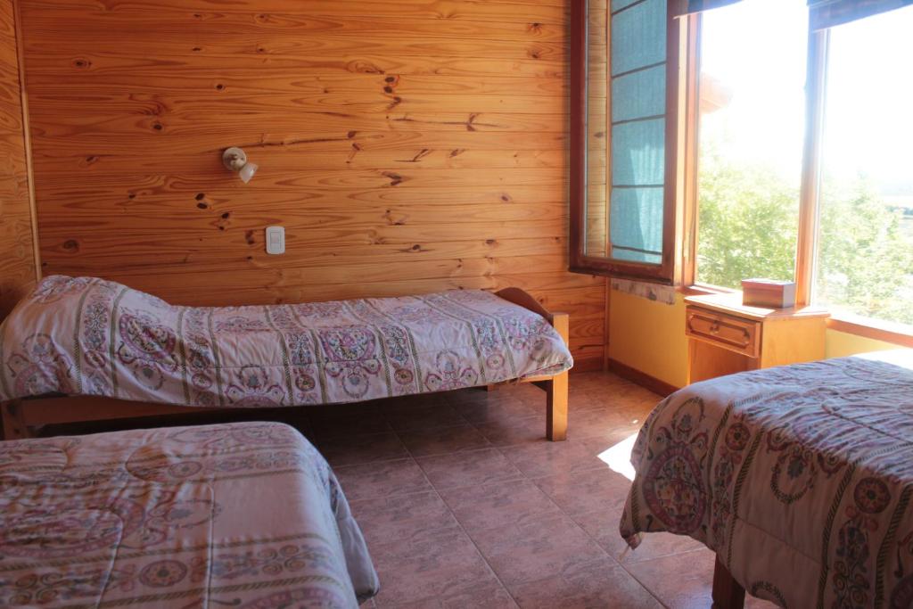 um quarto com 2 camas num chalé de madeira em Hospedaje Manantiales em El Calafate