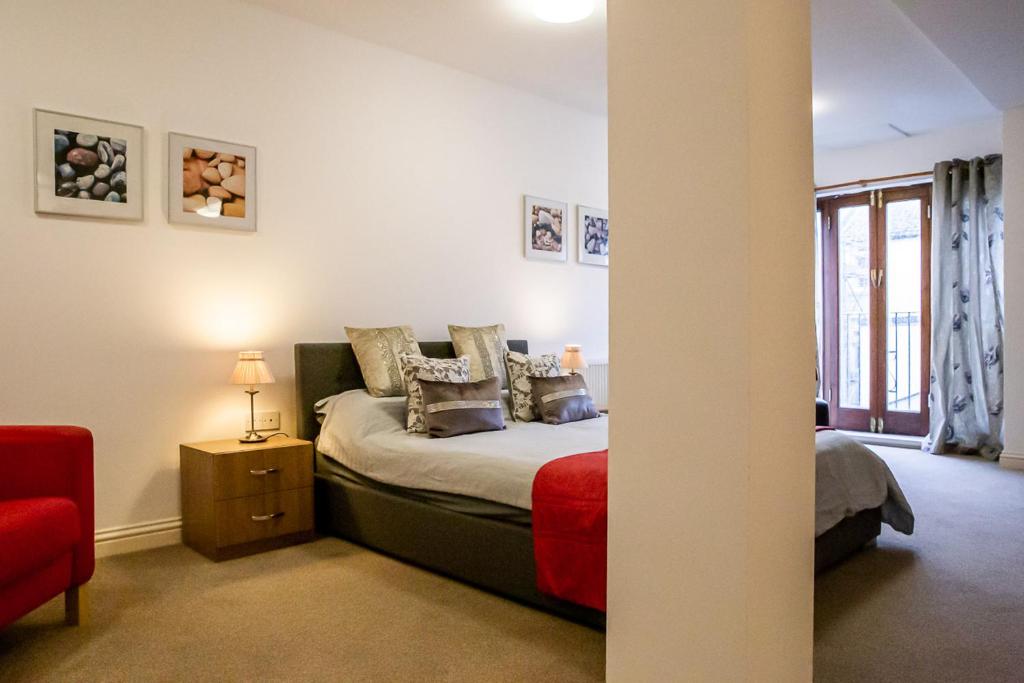 a bedroom with a bed and a red chair at Cavernous open plan town house in st Leonards in St. Leonards