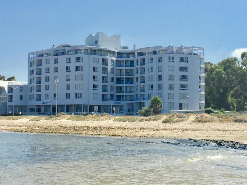 Ocean Breeze Hotel في ستراند: مبنى أبيض كبير على الشاطئ بالقرب من المياه