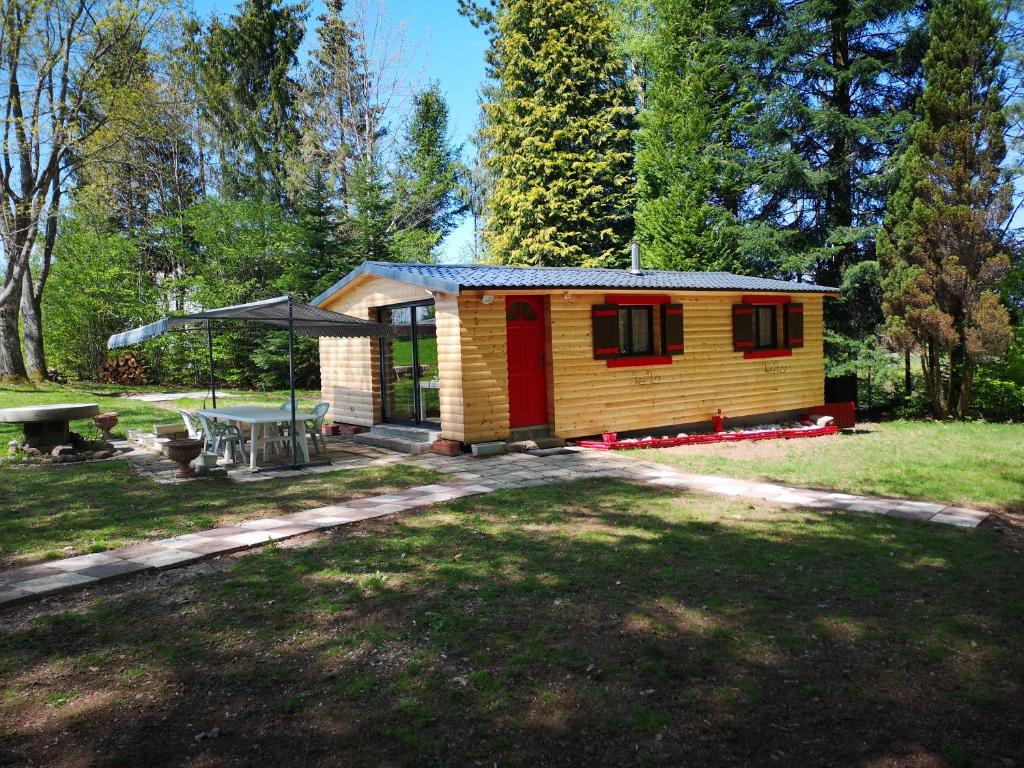 a small cabin with a picnic table in a yard at Chalet aux 3 Ours , Kota-Grill, sauna in Le Val-dʼAjol