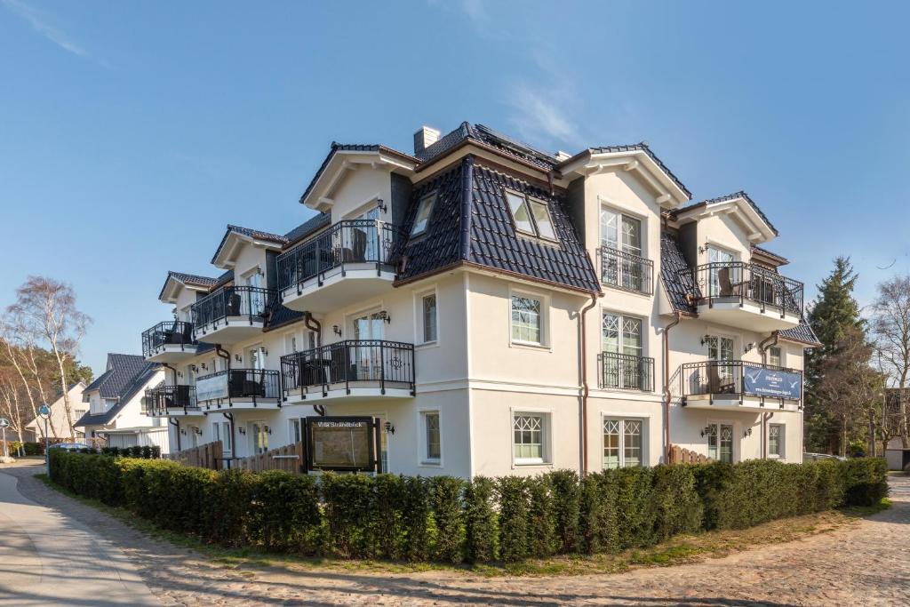 a large white building with balconies on a street at Villa Strandblick in Zingst