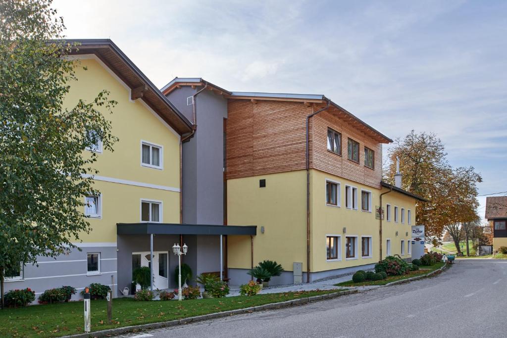 Tumeltsham的住宿－Hotel Gasthof-Strasser，一座大型黄色建筑,设有木屋顶